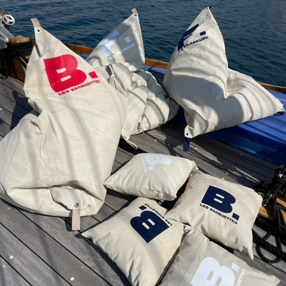 Poufs et coussins en voile de bateau recyclée de La Flanneuse. Ils sont personnalisés aux couleurs de l'entreprise marseillaise 
